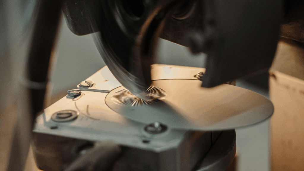 Máquina de lapidação com disco diamantado a polir a superfície de uma peça metálica, criando um acabamento brilhante e refinado.